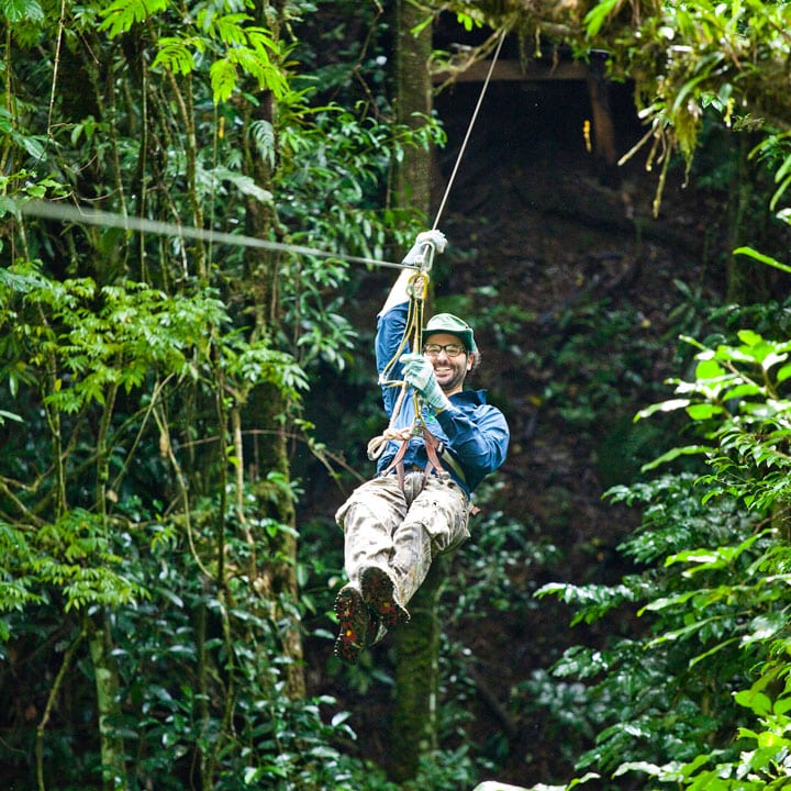 Smiling man riding zipline